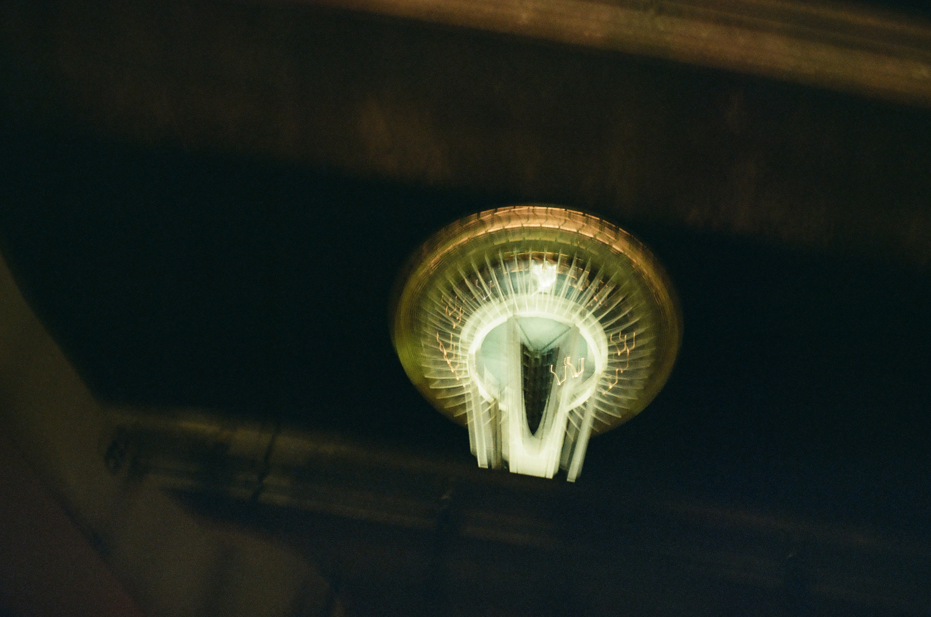 A green-white illuminated ring sits above a narrow tower shaft while a large dark shape enters from the left.