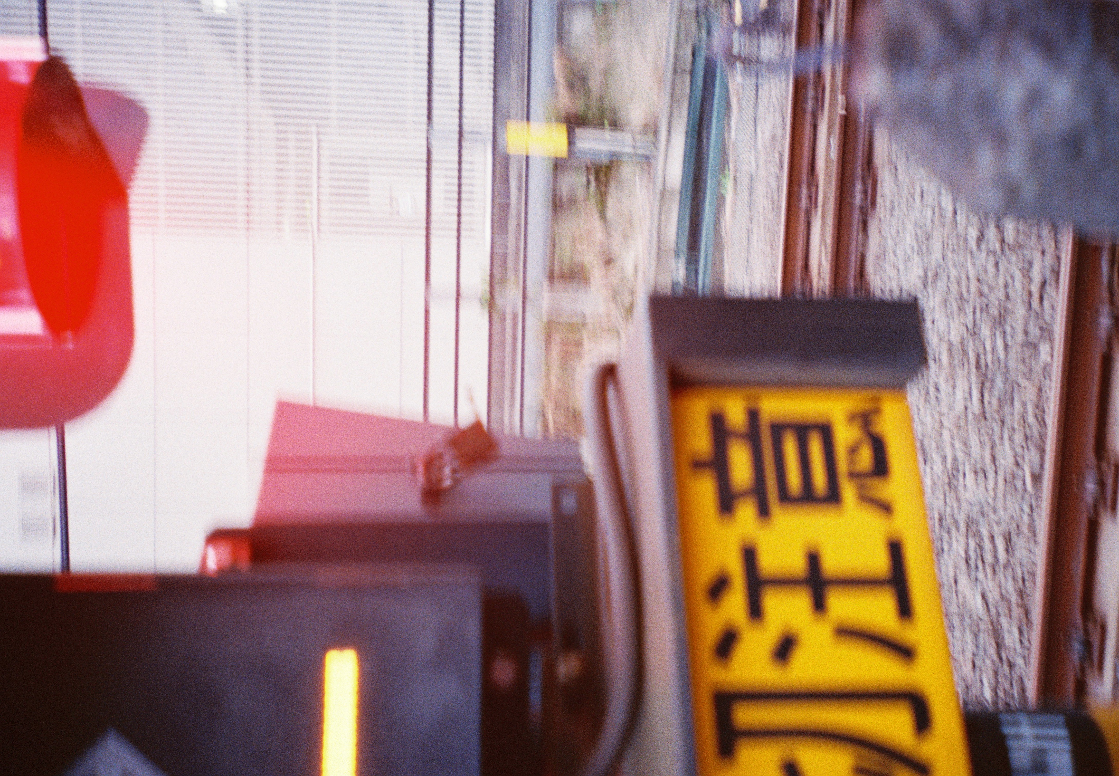 A red lamp hangs at the top above a yellow sign reading 注意, with rails, gravel, and a yellow post beyond.