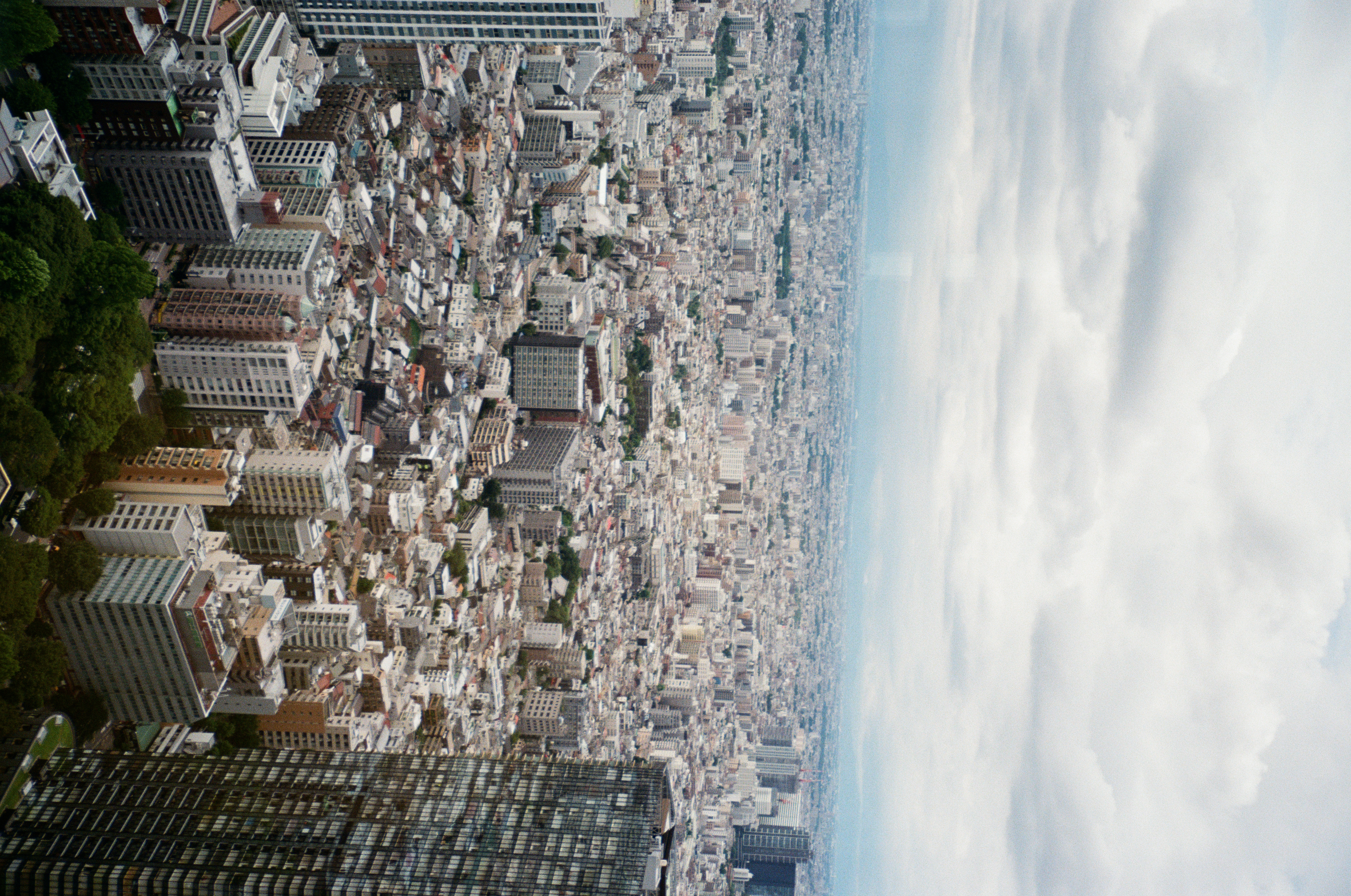 Mid-rise and low buildings stretch unbroken toward a soft, silver horizon, with a dark high-rise cropped along the right edge.