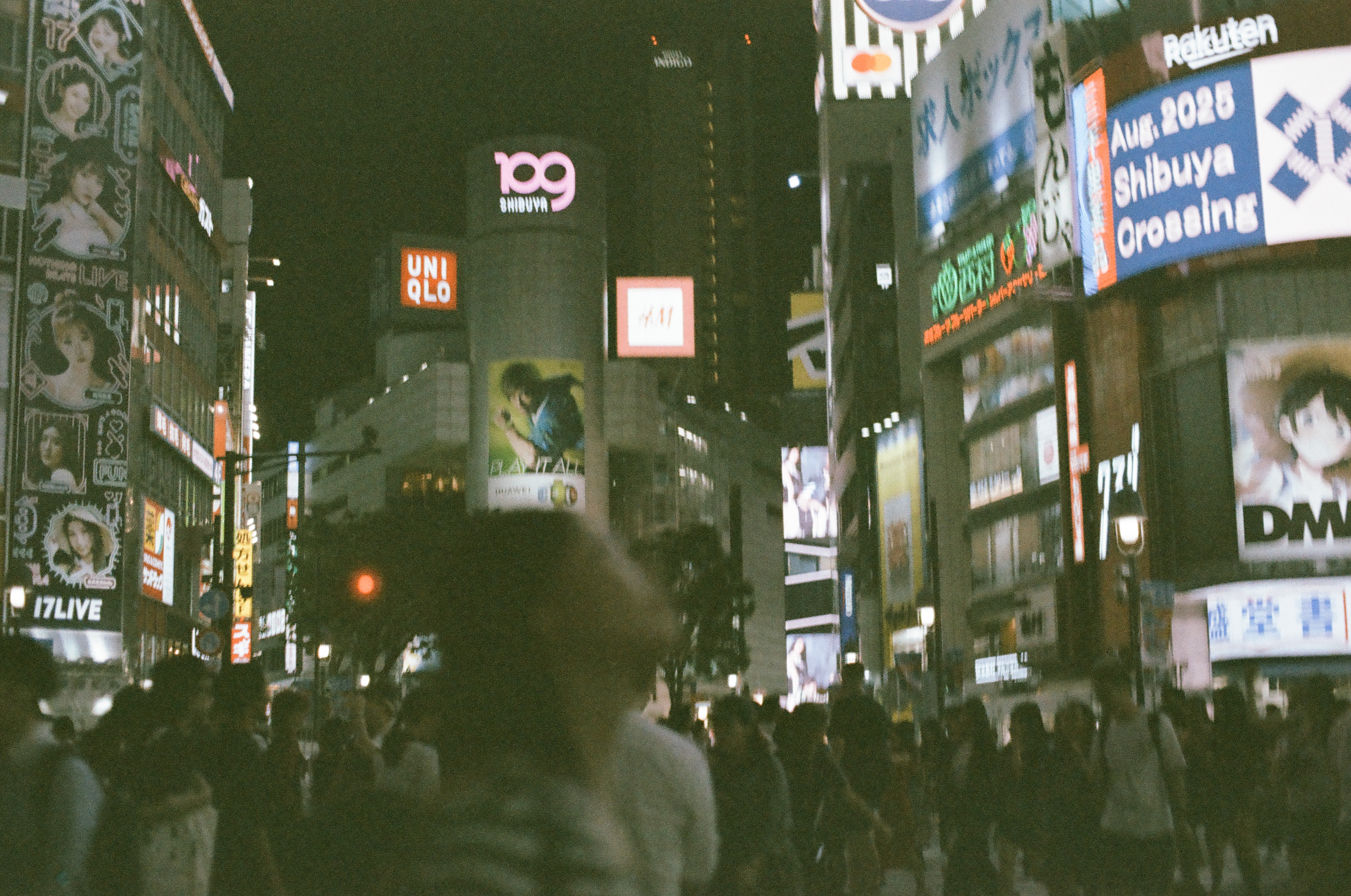 A tower lettered '109 SHIBUYA' rises among illuminated signs reading UNIQLO, DMM, and 17LIVE above a crowd at a night crossing.