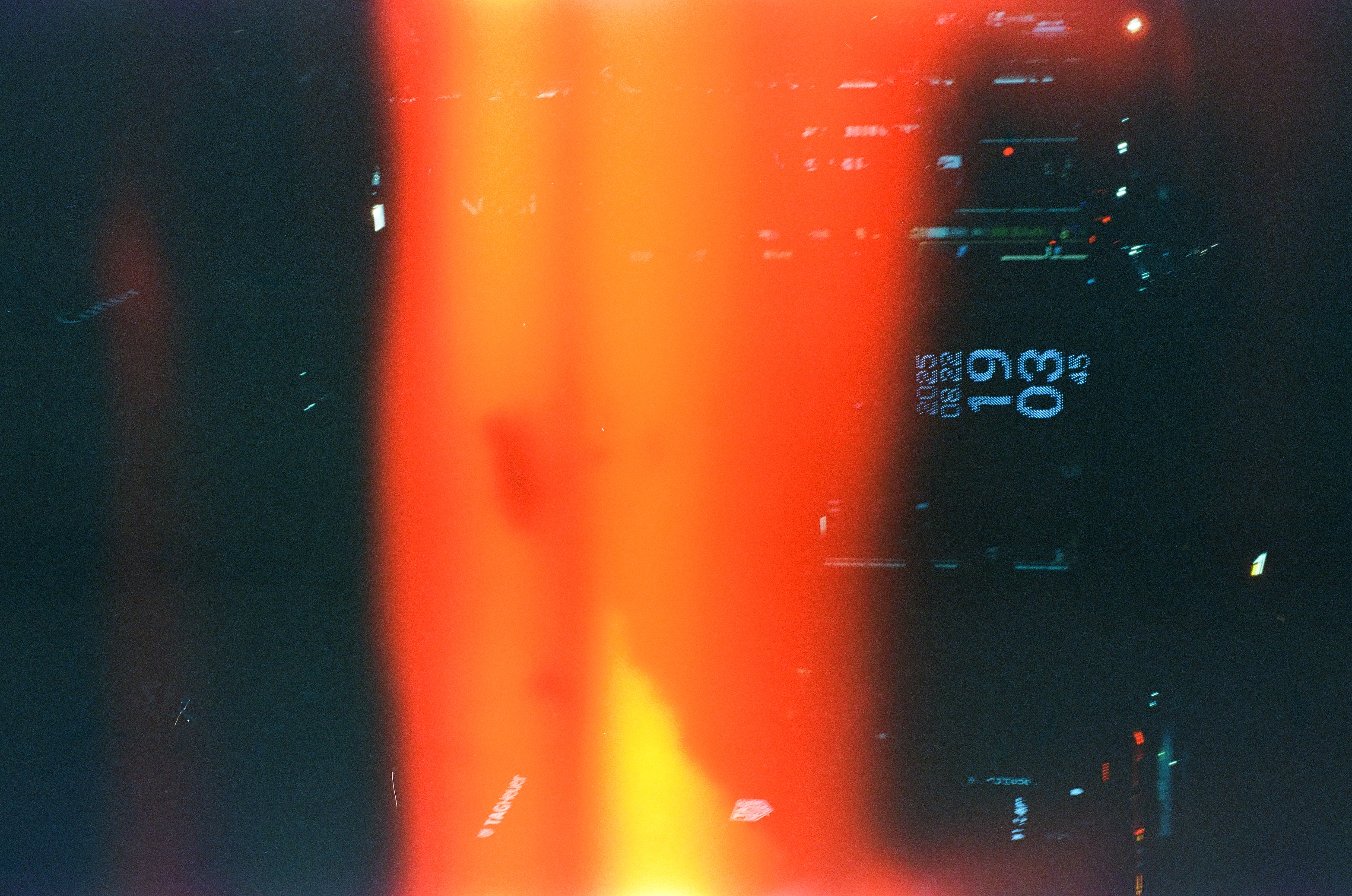 Horizontal bands of red, orange, and yellow light cross a dark scene above a small blue dotted numeric readout and scattered building lights.