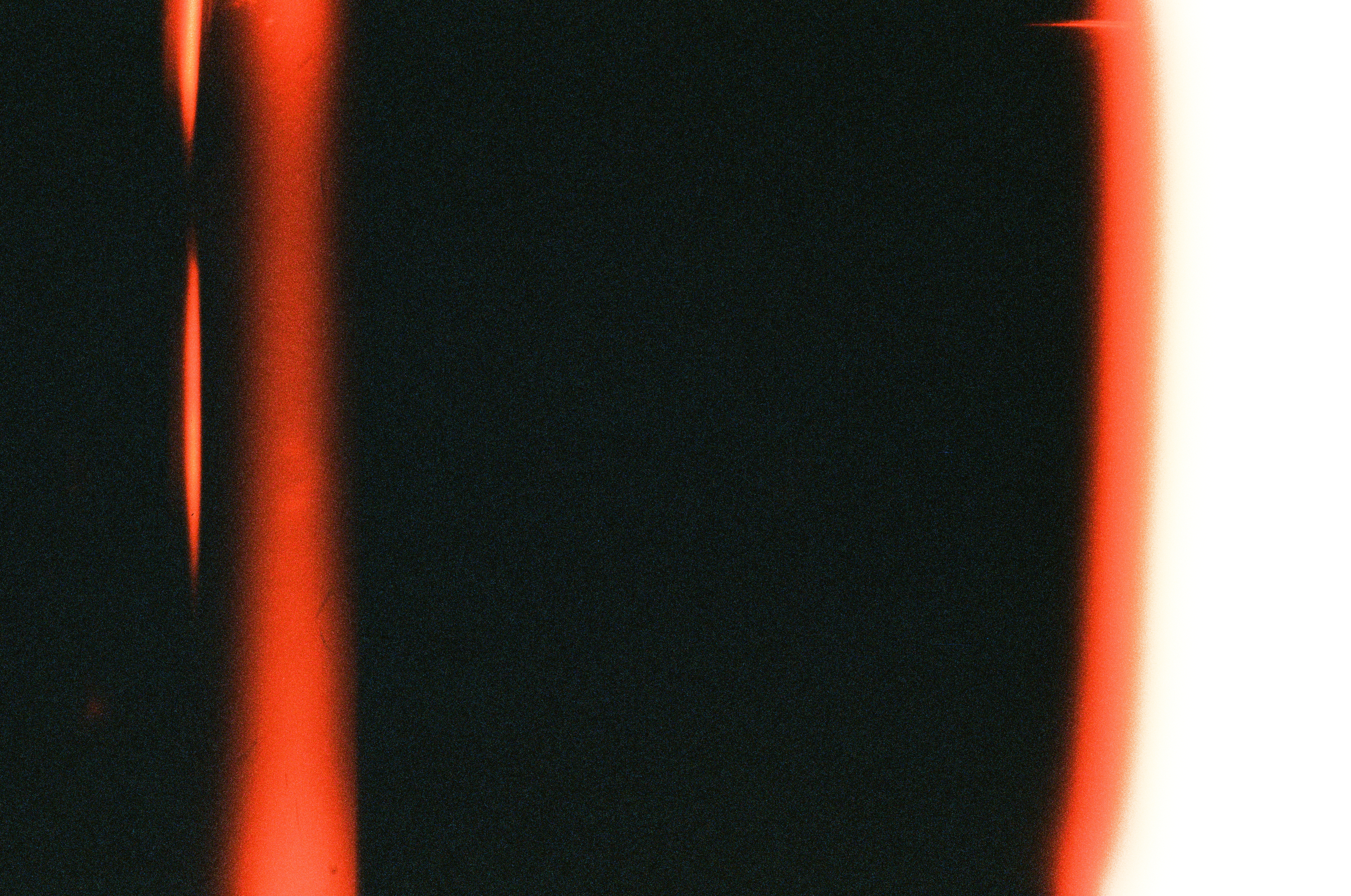 Vertical bands of red-orange light leak split a mostly black frame, with the right edge fully blown out to white.