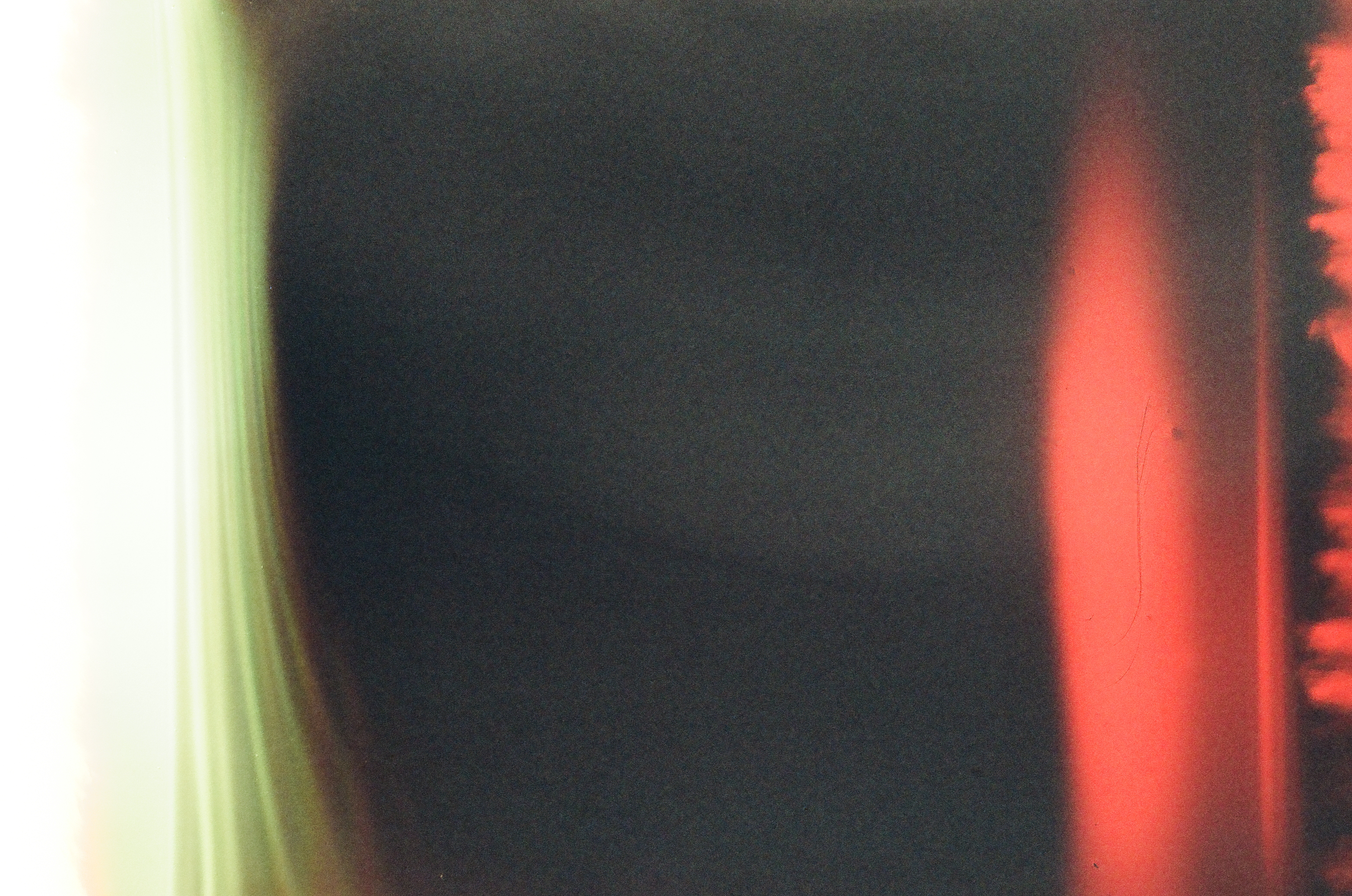A hazy pale gradient bleeds into solid black at the frame's center, with a jagged red-and-dark silhouette fringing the right edge.