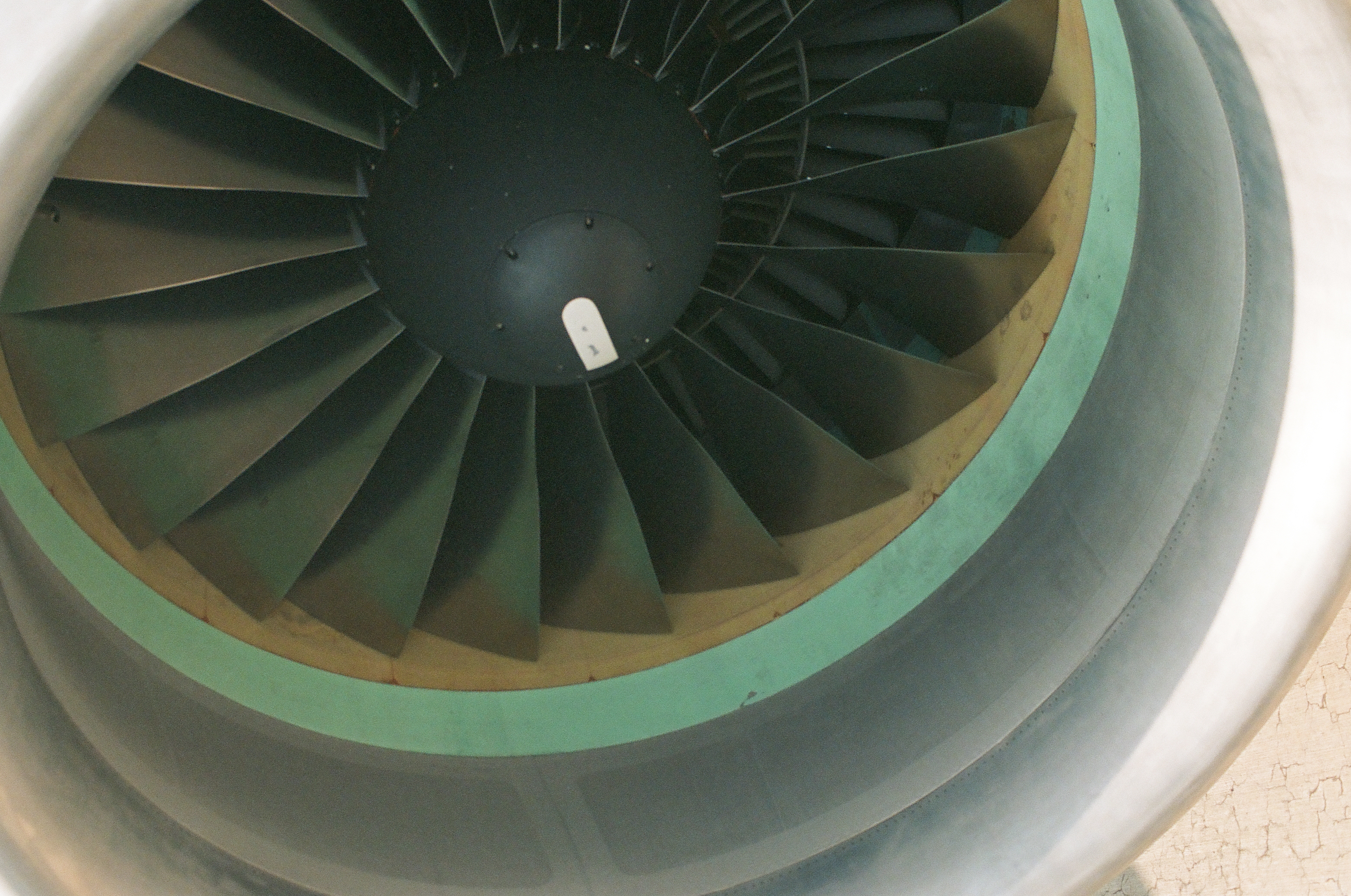 Dark aircraft turbine blades radiate around a black central hub inside pale metallic and mint-colored circular housings.