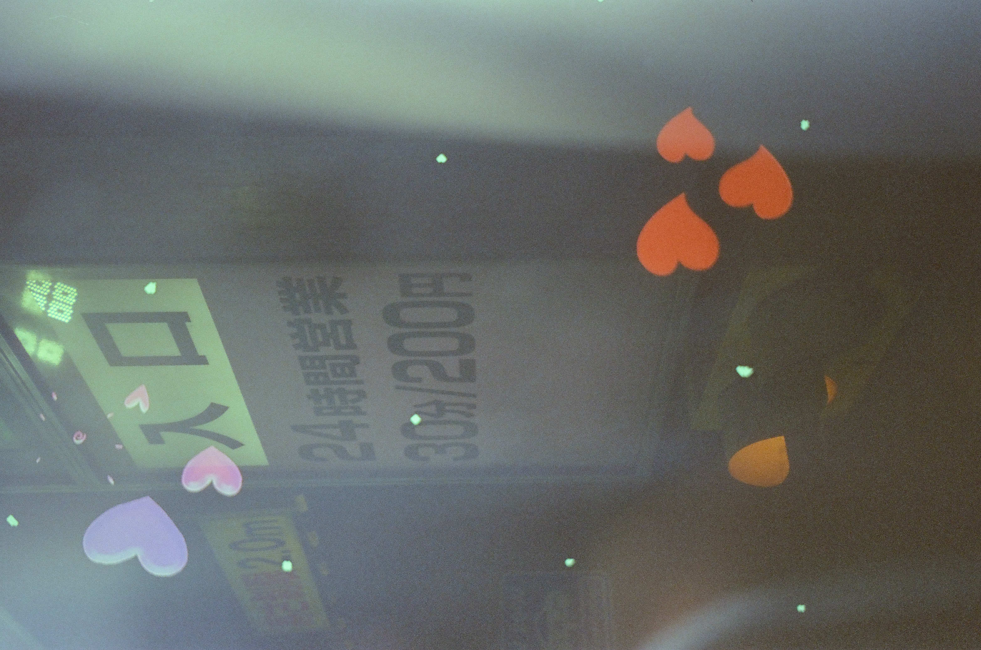 A vertical sign displays Japanese text reading '入口' above pricing information including the numerals 24, 30, and 200, overlaid by lavender, pink, and orange heart shapes.
