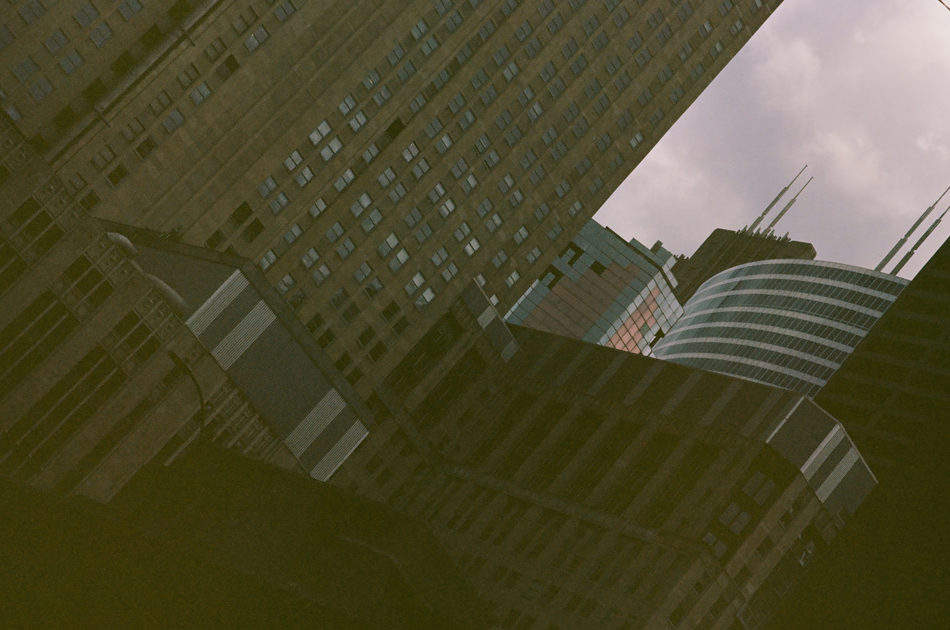 A rounded striped facade bends between taller windowed buildings in a tightly framed upward street view.