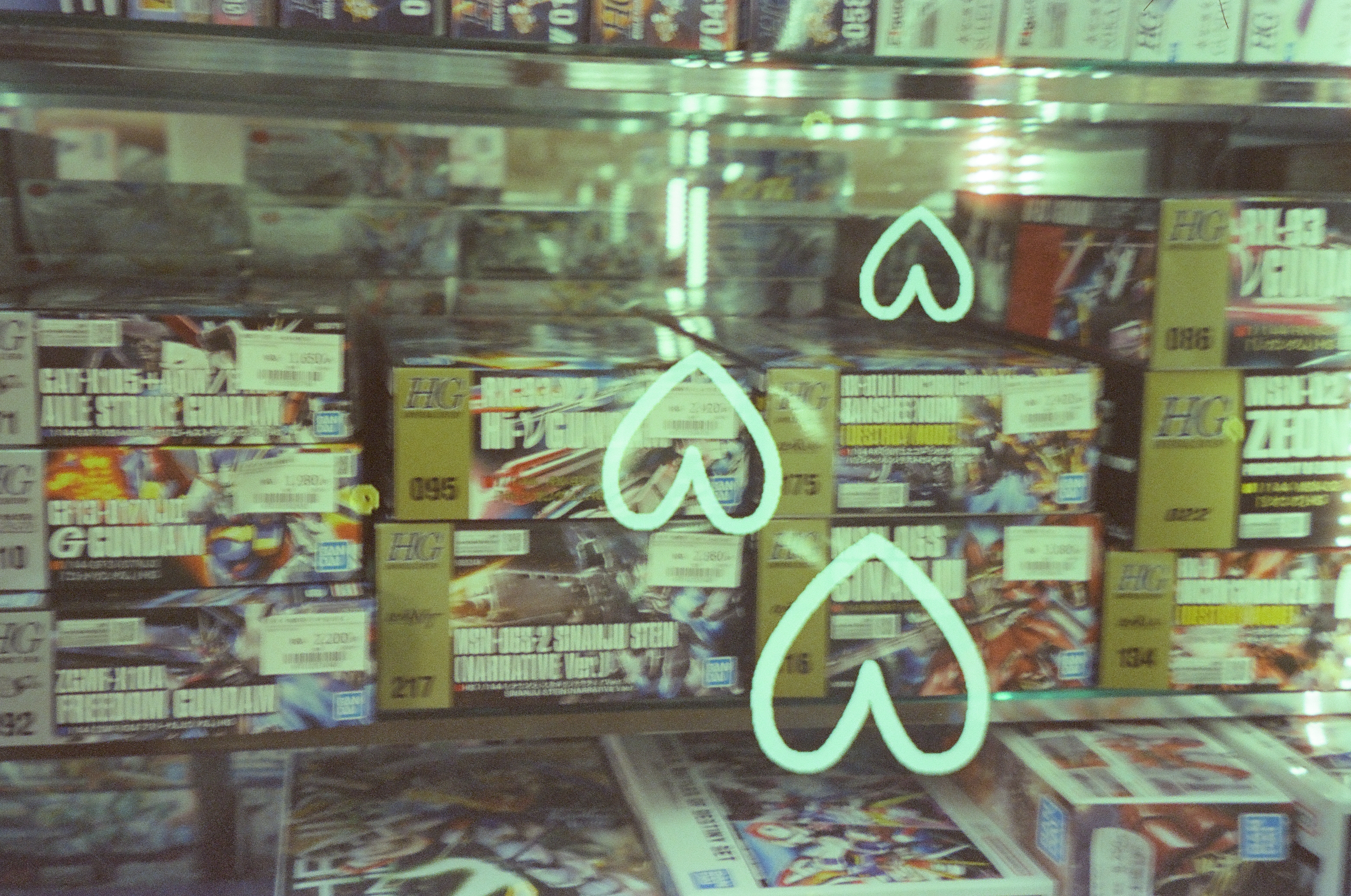 Three large white heart outlines float across a window densely covered with small printed labels.