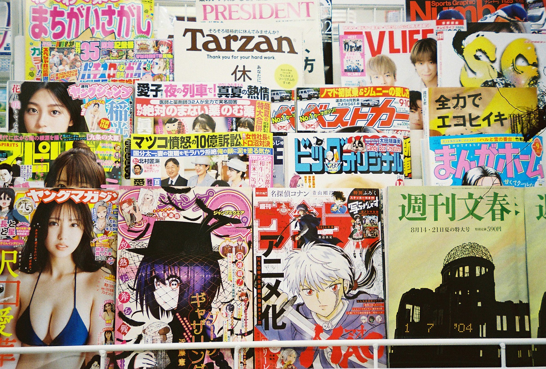 A magazine rack displays dozens of tightly packed covers with Japanese and English titles including 'Tarzan' and 'PRESIDENT,' alongside a domed ruin silhouette cover.