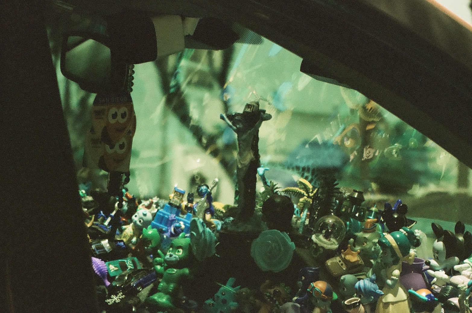 A crowded dashboard display appears through green reflections beneath the dark diagonal edge of a car window.