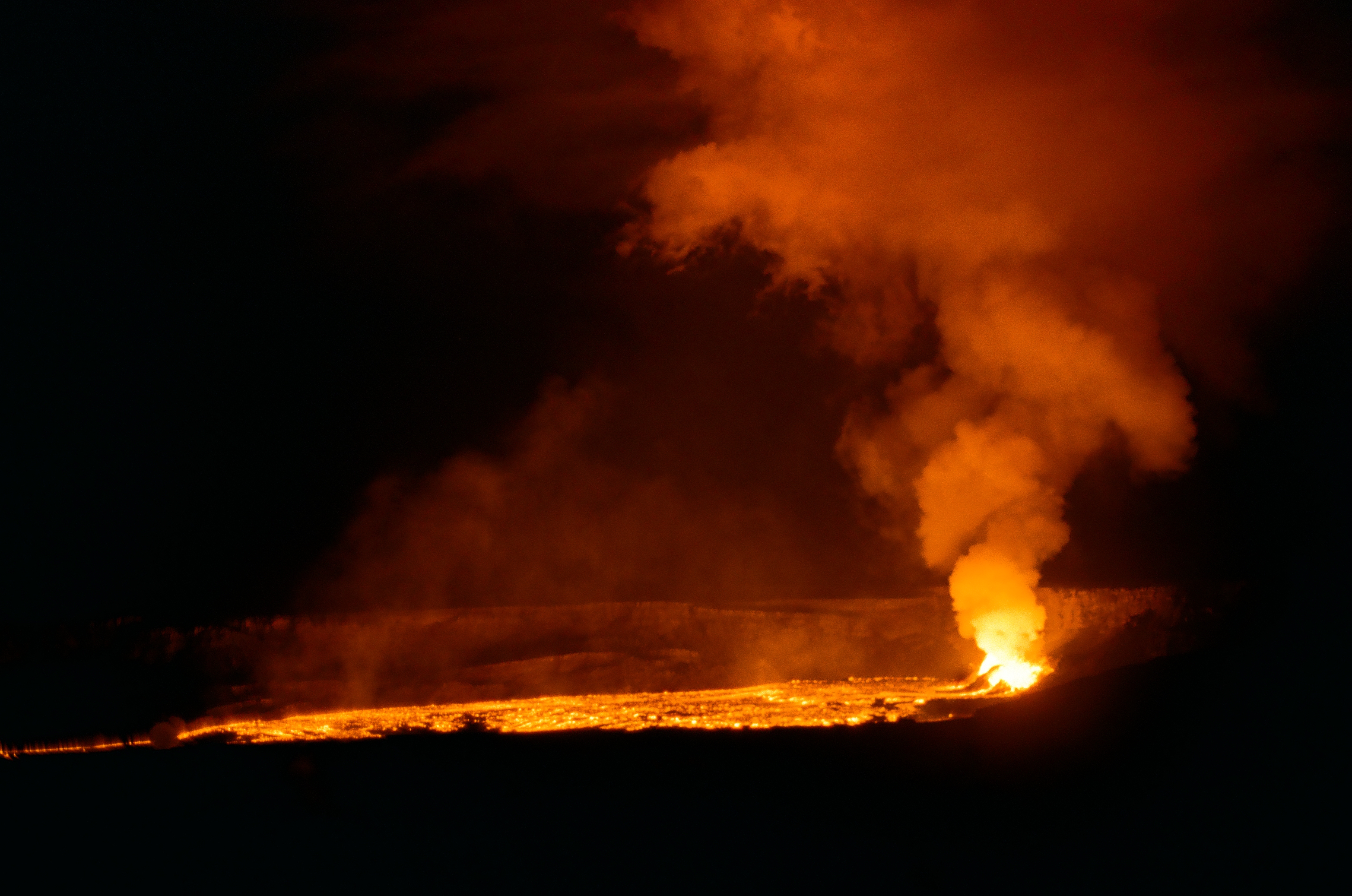 A bright lava vent and horizontal molten channel illuminate a dense orange smoke plume against night.
