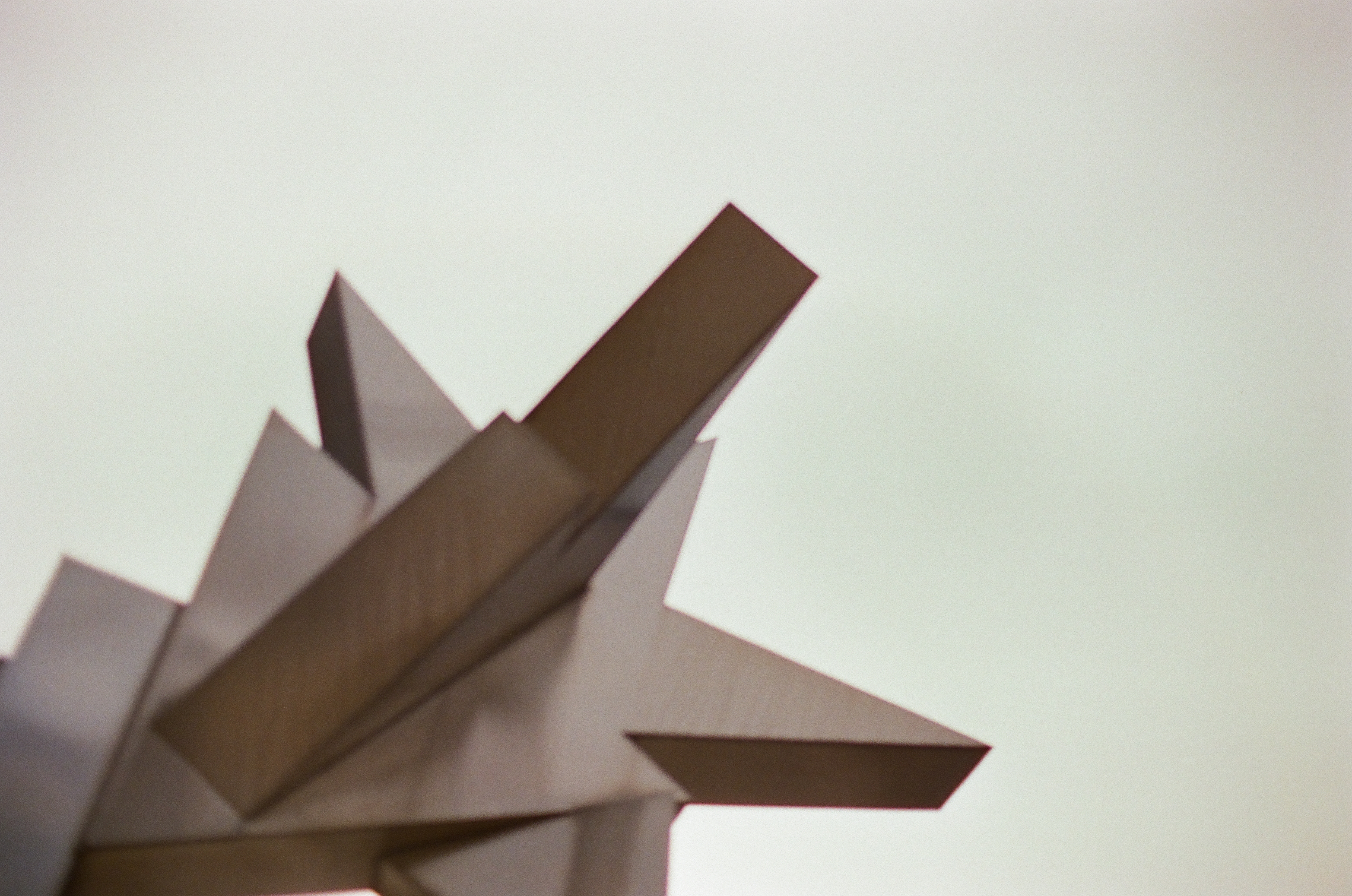 Several angular metal forms thrust upward in overlapping directions against a nearly white sky.