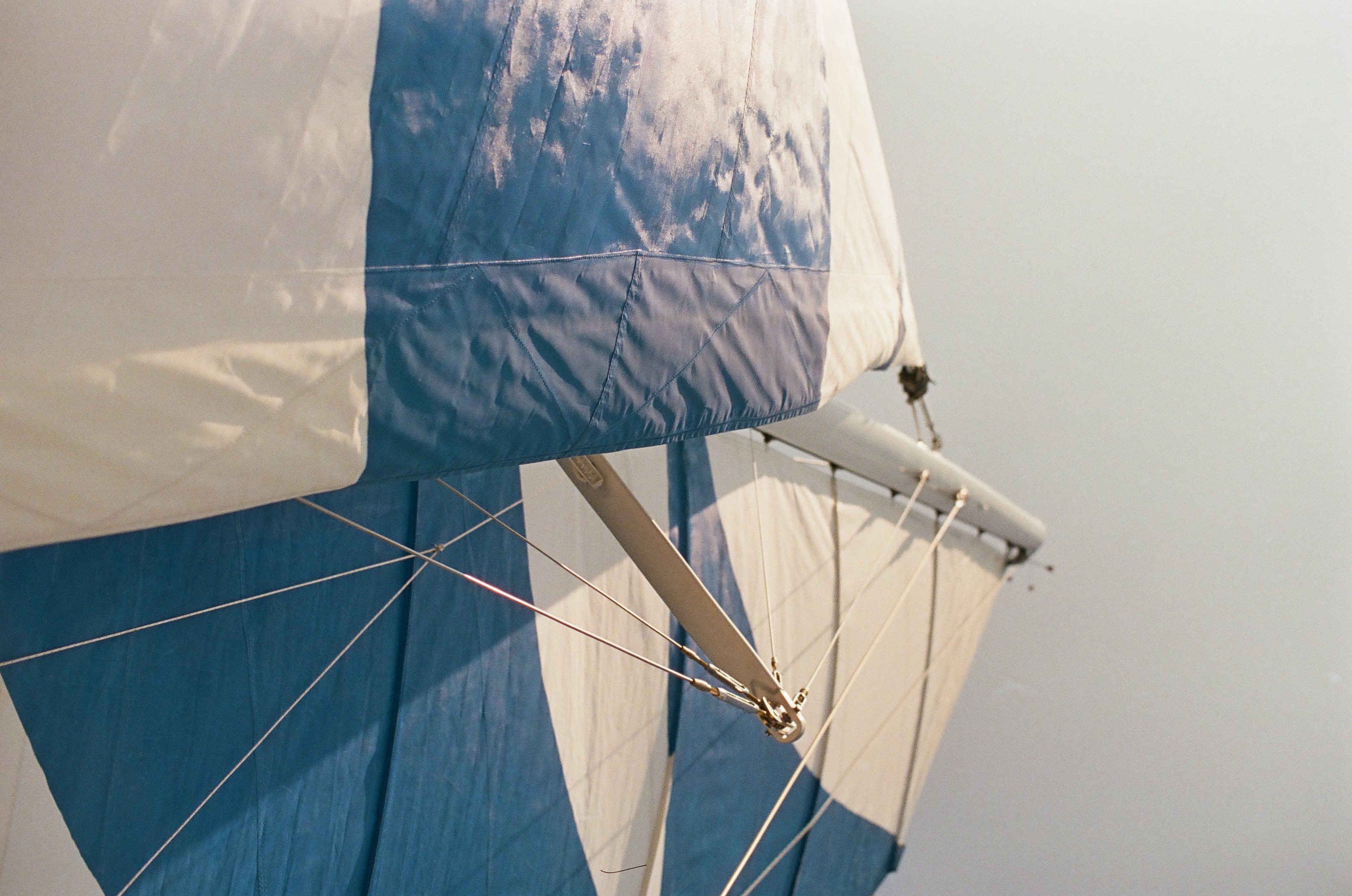 White and blue fabric panels stretch around ropes and metal supports beneath a clear open sky.
