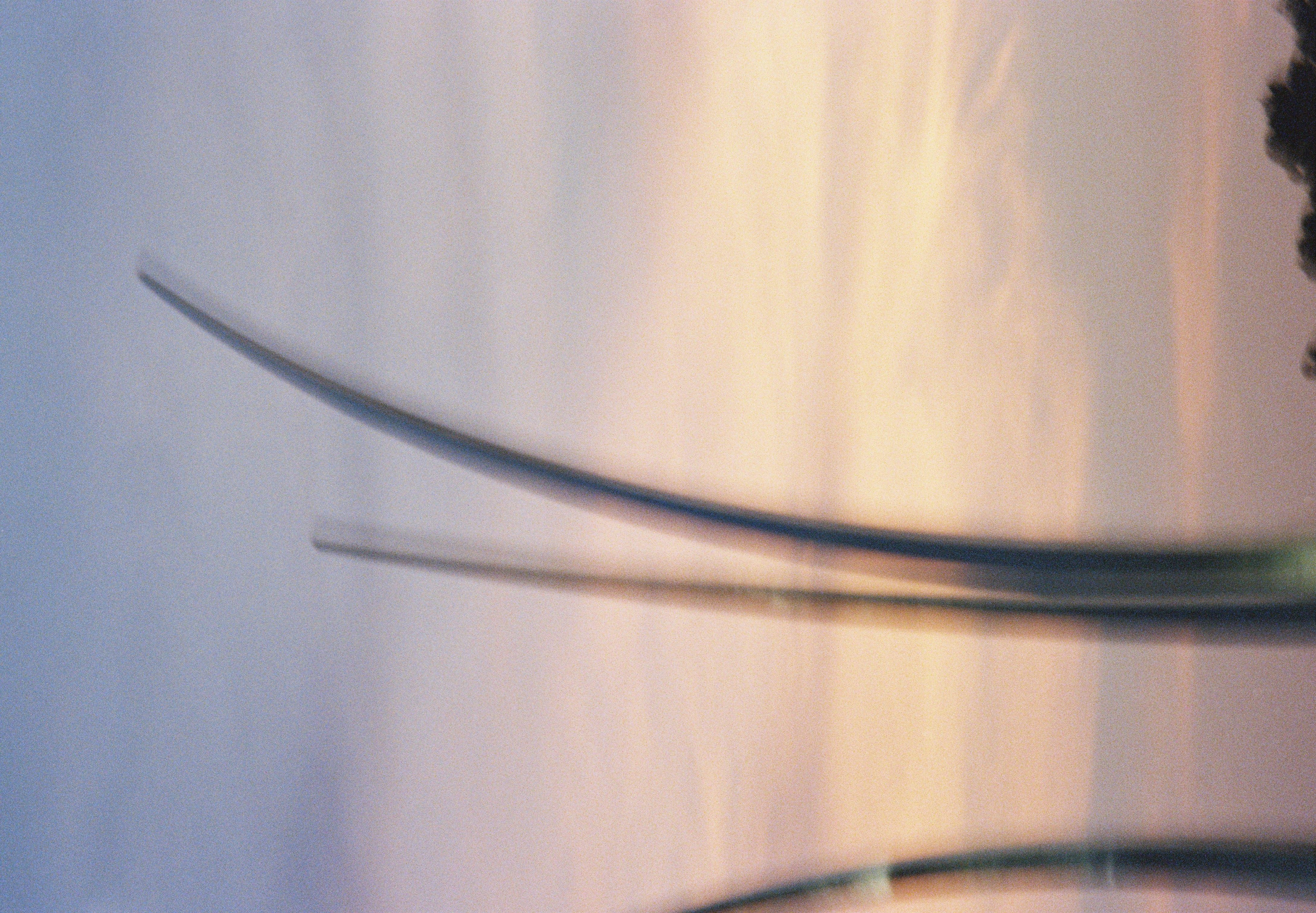 Slender curved spires rise in soft focus against a sky banded with peach and lavender clouds, with dark treetops in the lower right corner.