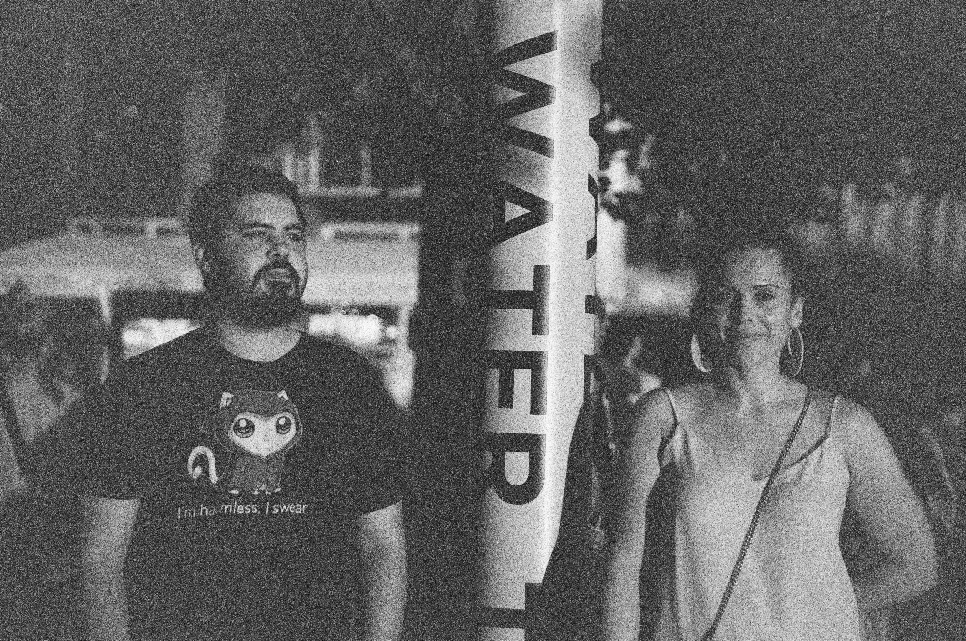 Two forward-facing figures overlap with pale reflected faces and dark horizontal bands in a layered monochrome exposure.