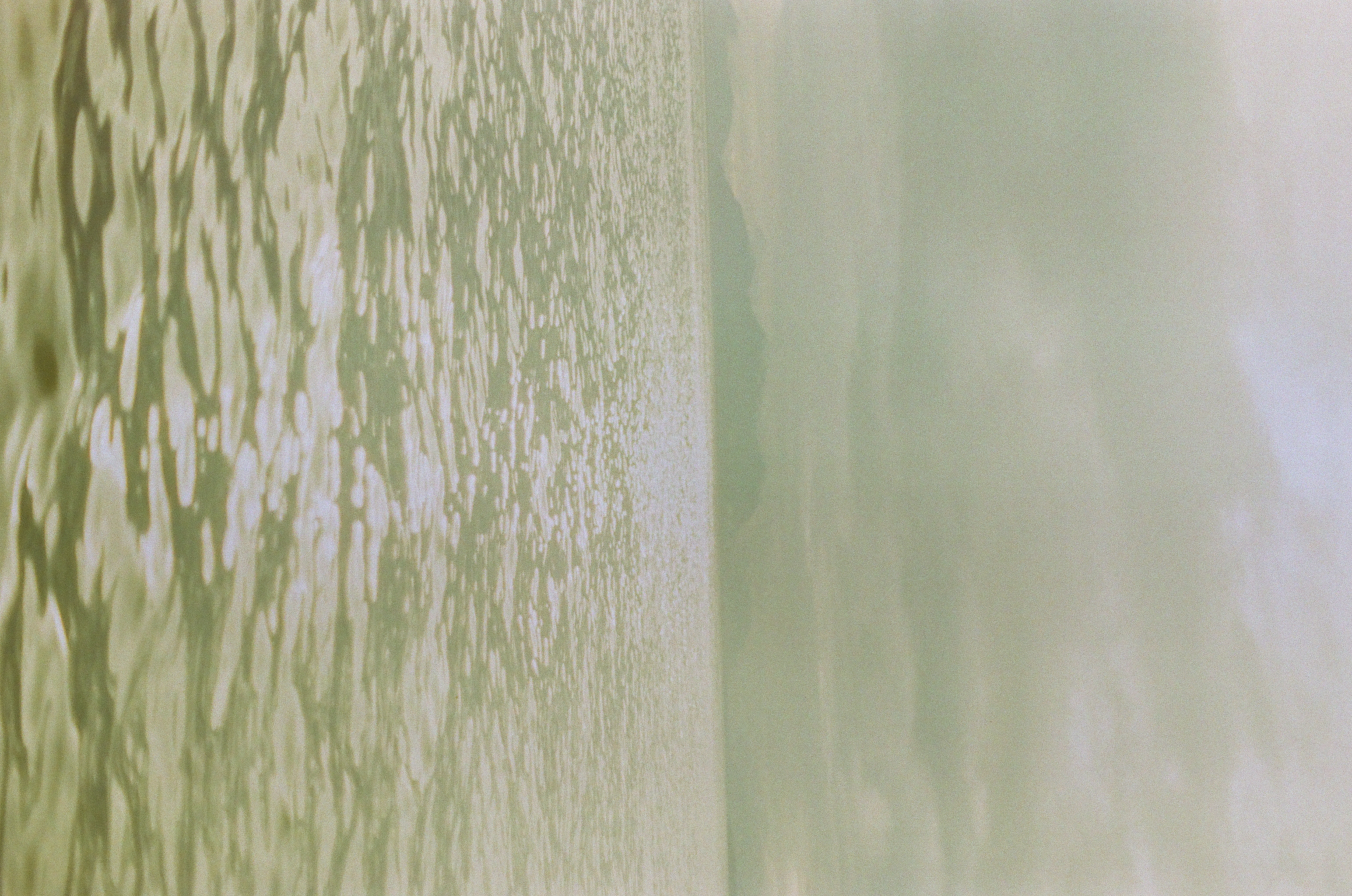 Small ripples spread across green-gray water toward a faint horizon under a broad overcast sky.