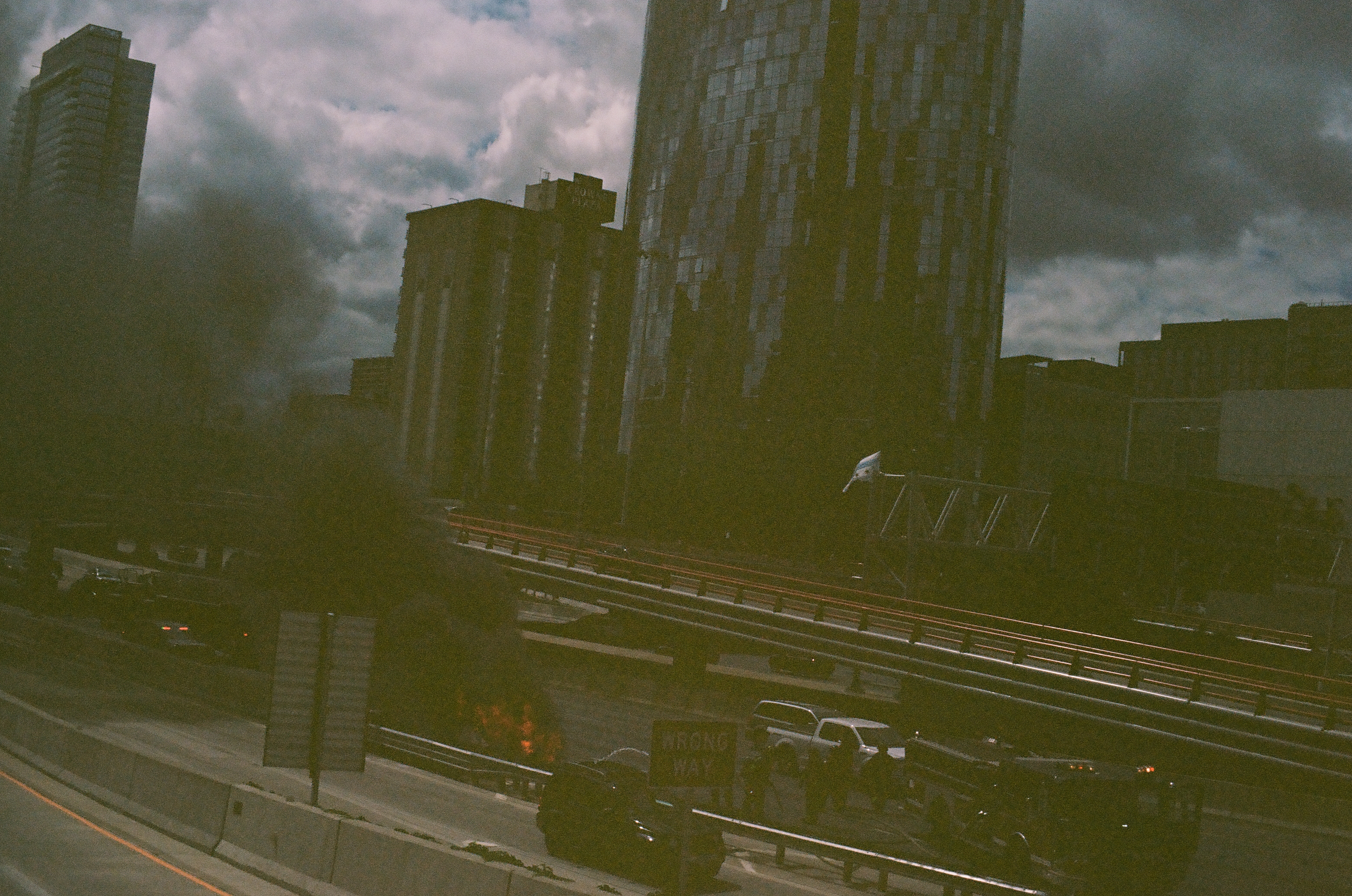 Rail lines and barriers cross the foreground below closely packed towers under a heavy gray sky.