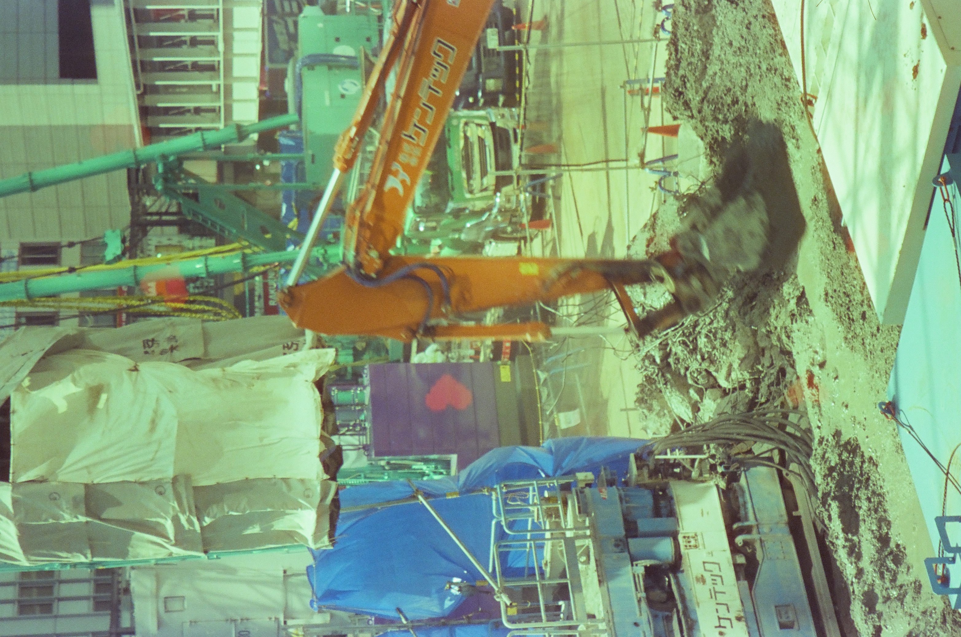 Colored heart shapes overlay an orange excavator, blue barriers, and broken ground at a street construction site.