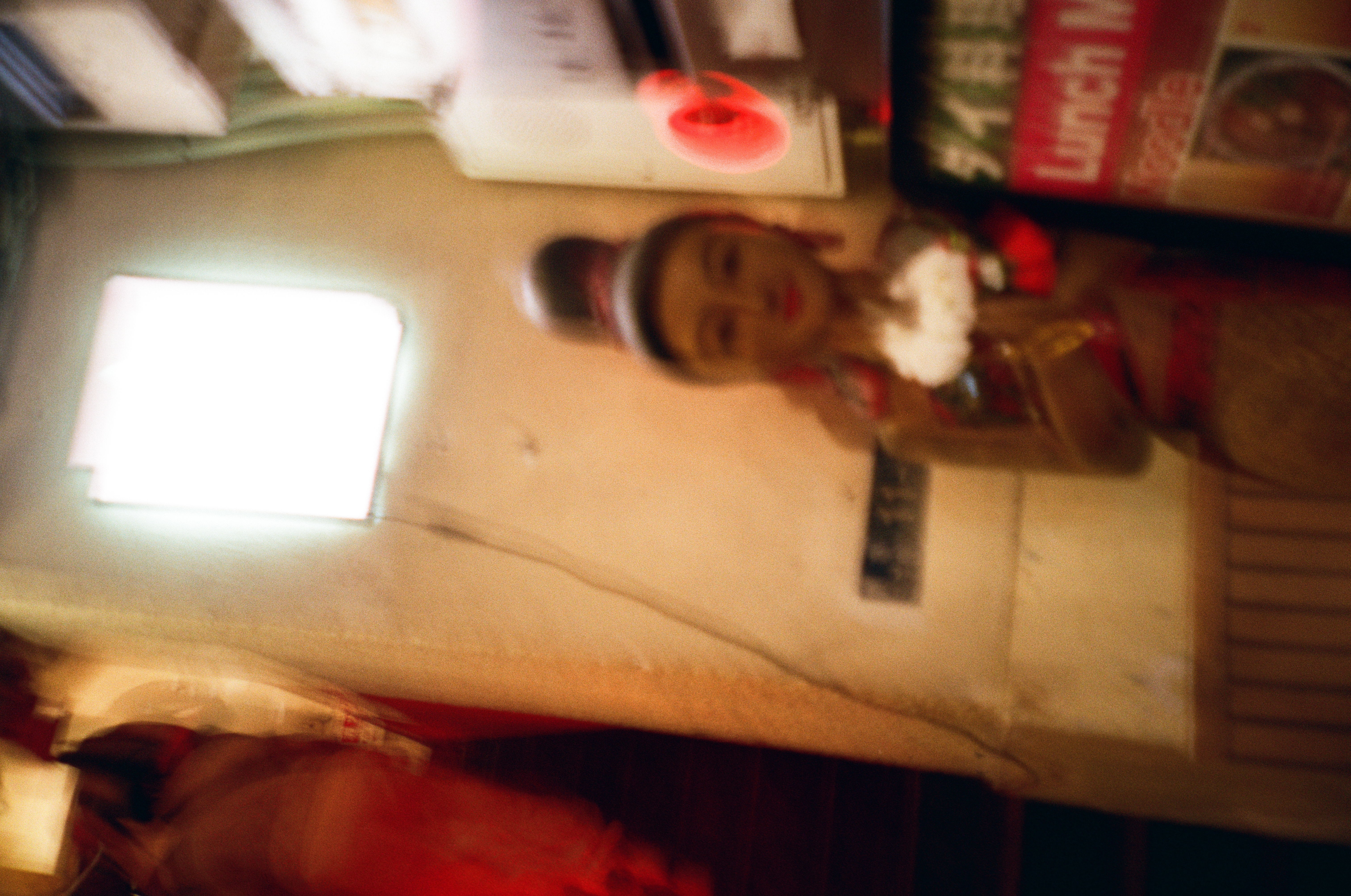 A blurred painted statue of a woman in traditional dress holds white flowers beside a red sign partly reading Lunch.