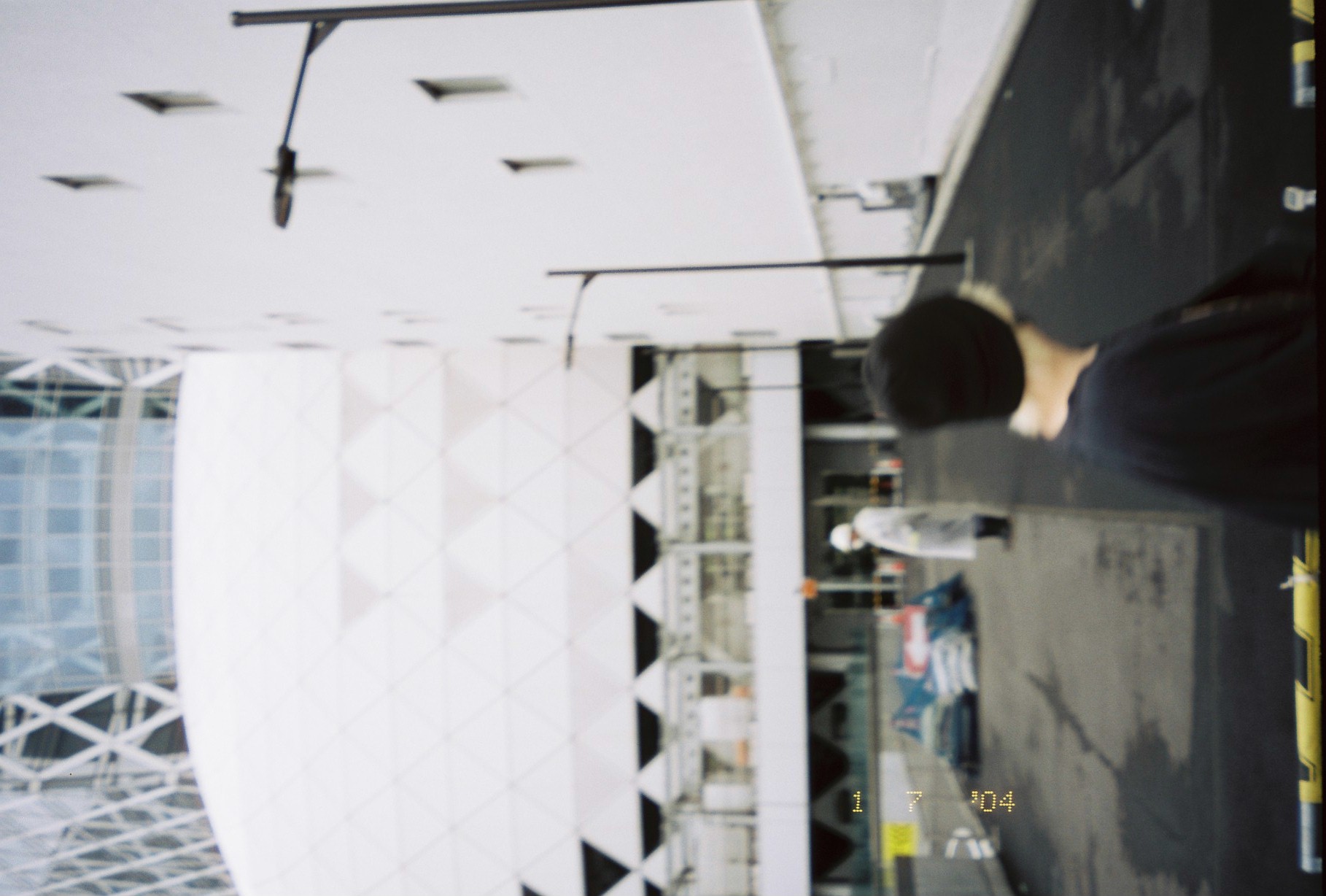 A large white dome tiled in triangular panels rises above a fenced work yard where a figure in white stands near stacked materials.