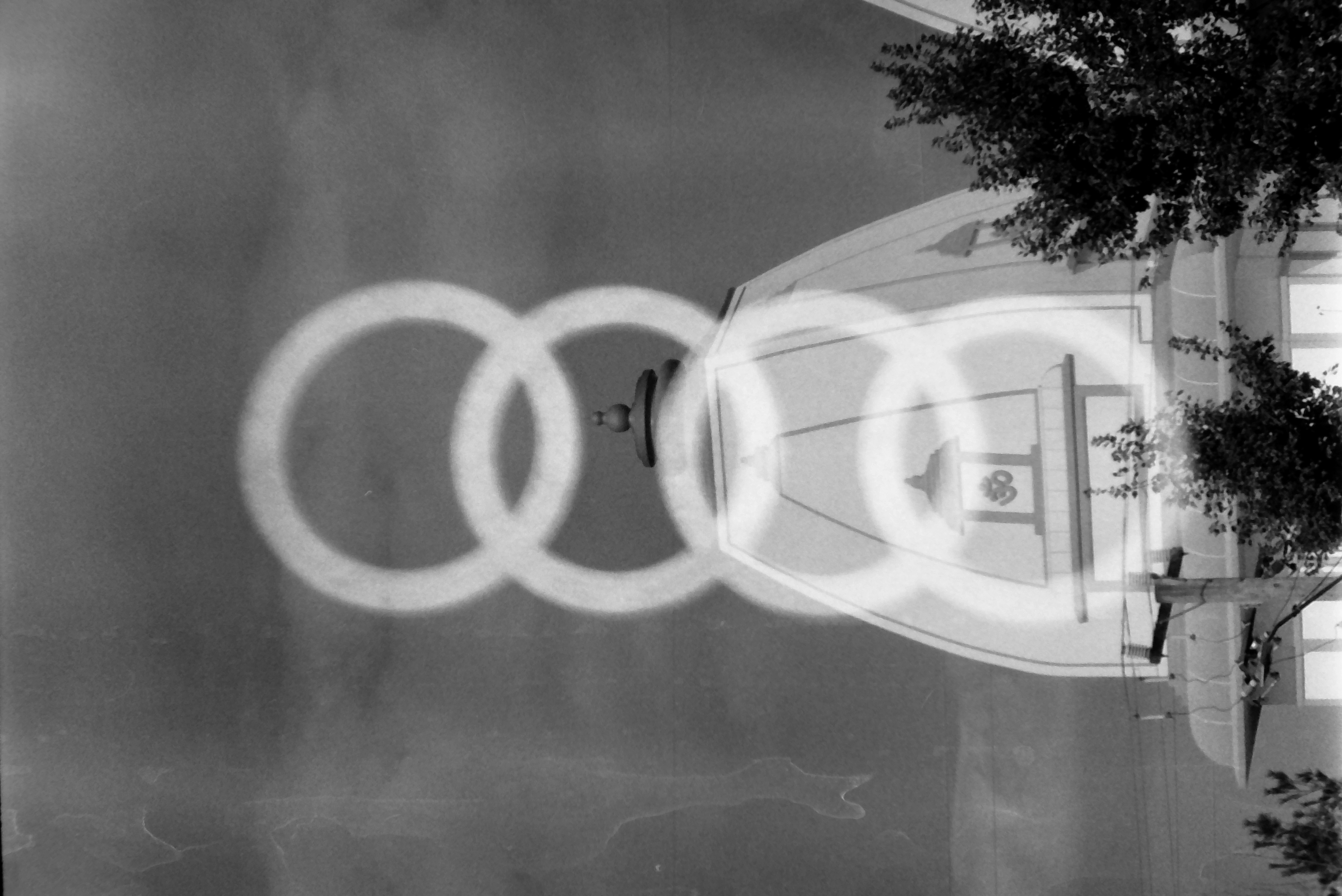 Four glowing overlapping rings stack vertically over a pale tower topped by a dome and finial, with a leafy tree at the lower right.
