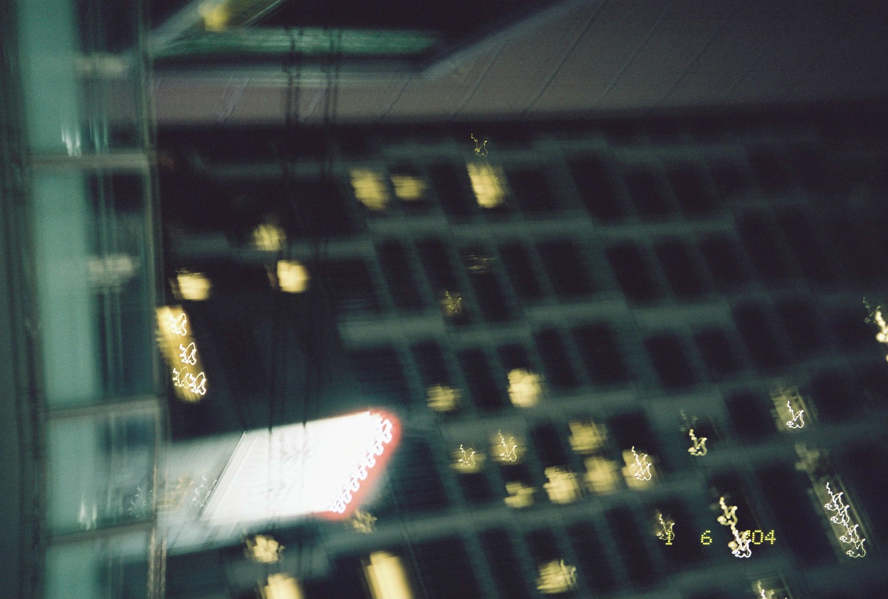 Scattered lit windows on a dark high-rise are dragged by camera motion into loops and scribbles of gold light against the glass grid.