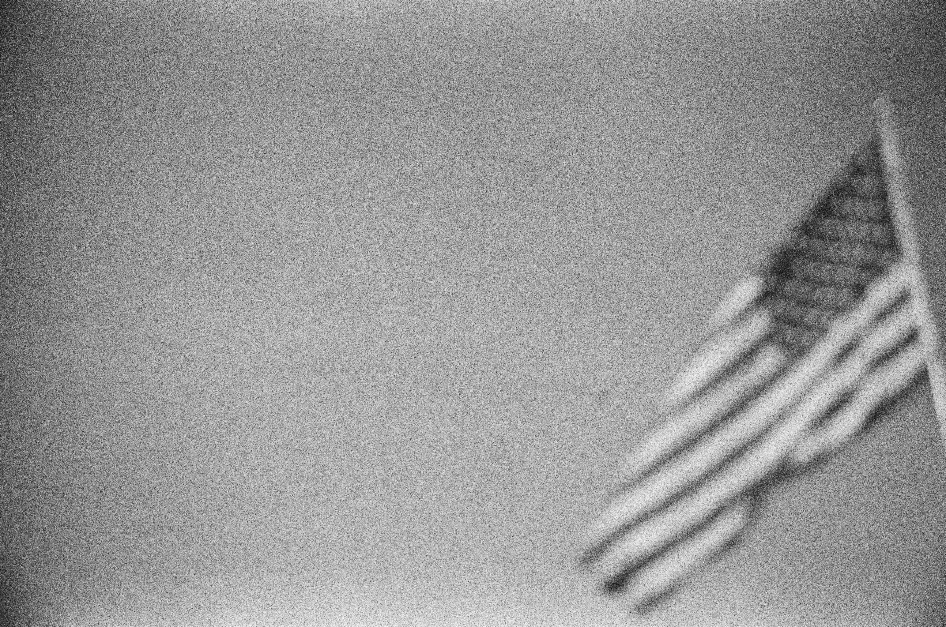 An American flag drifts softly out of focus against a broad pale and nearly empty sky.