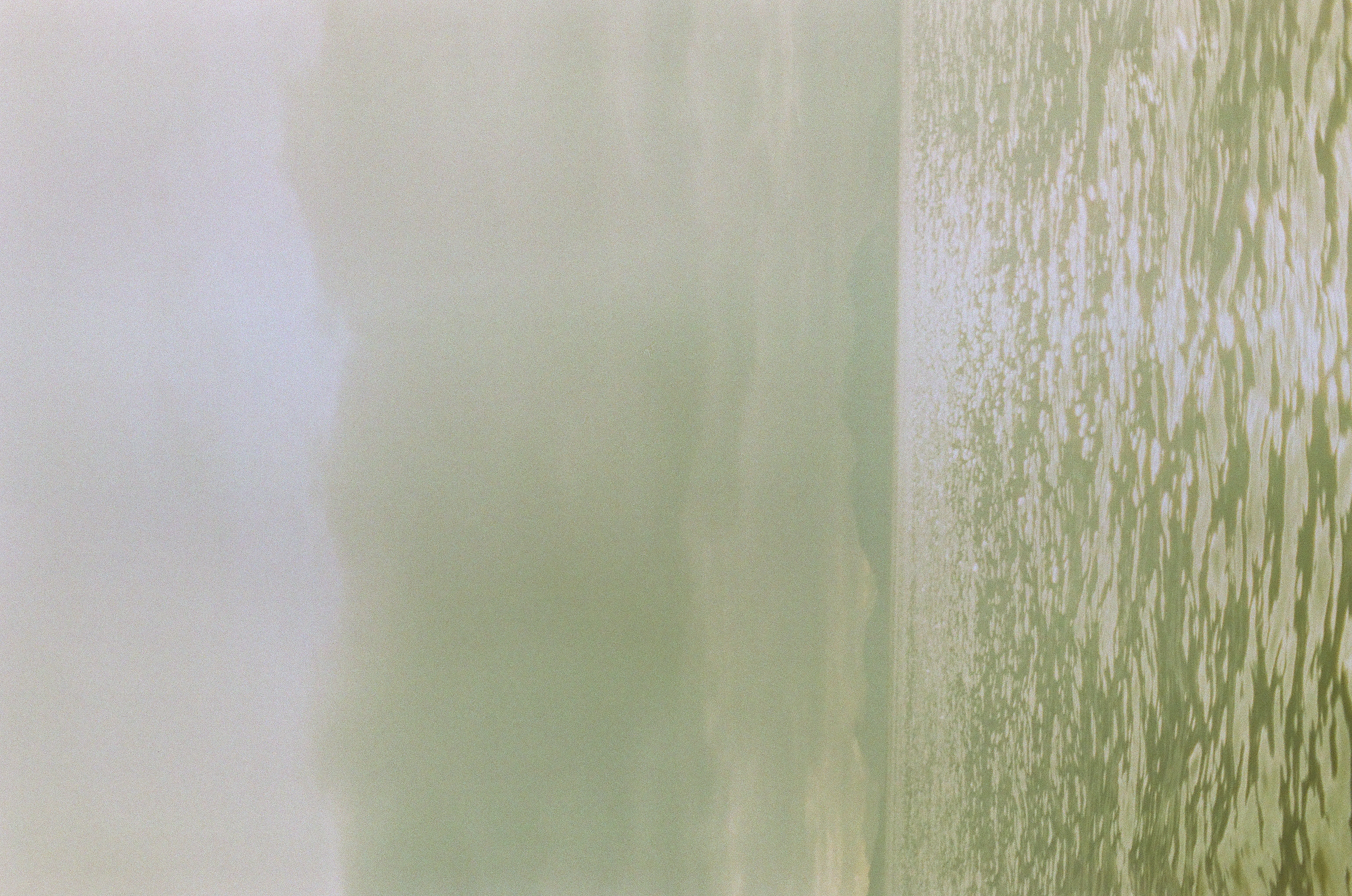 A pale green sea fills the lower half beneath soft gray clouds and a faint distant horizon.
