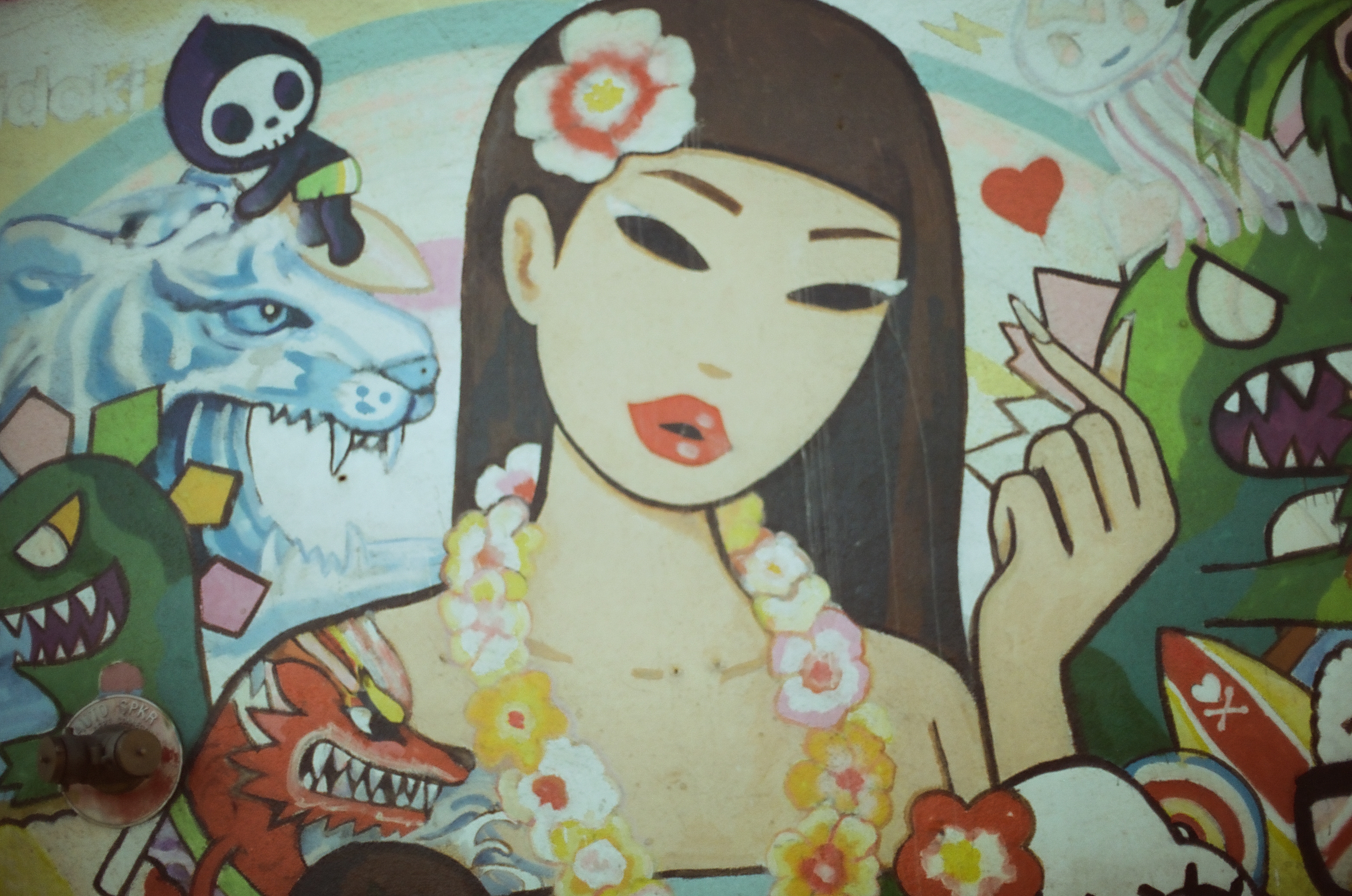 A bright mural combines a woman, flowers, skull, wolf-like animal, green monster, and other cartoon figures.