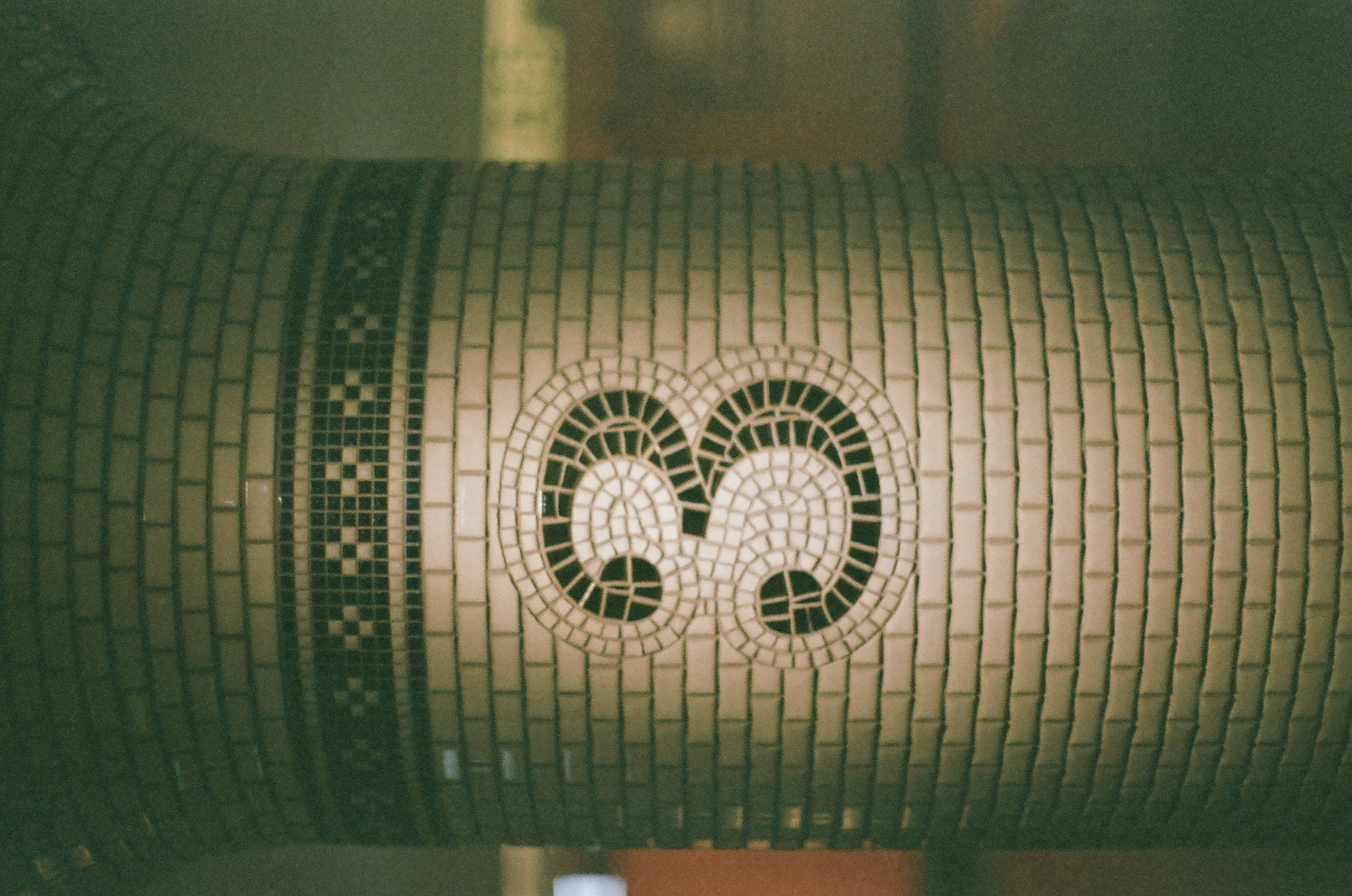 The mosaic numeral three fills a rounded pale tiled column beneath a narrow dark geometric band.