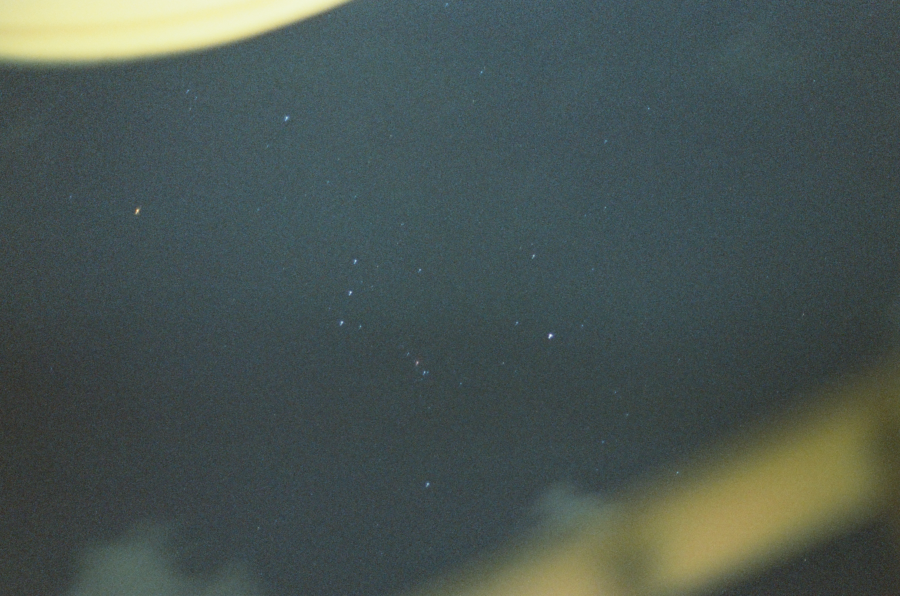 A field of small stars fills dark blue sky between broad out-of-focus yellow edges.