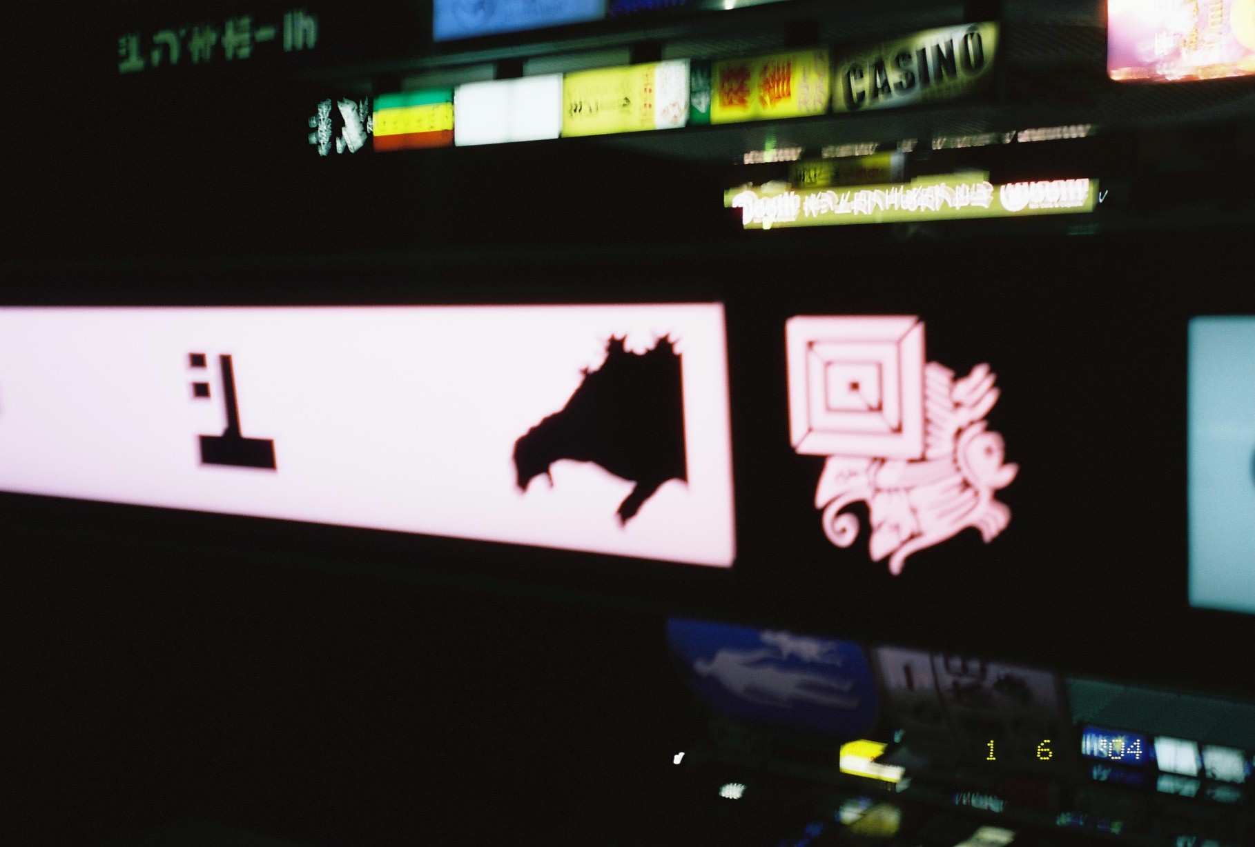 A pink illuminated signboard displays a large black creature silhouette and a single katakana character above a vertical CASINO sign column.
