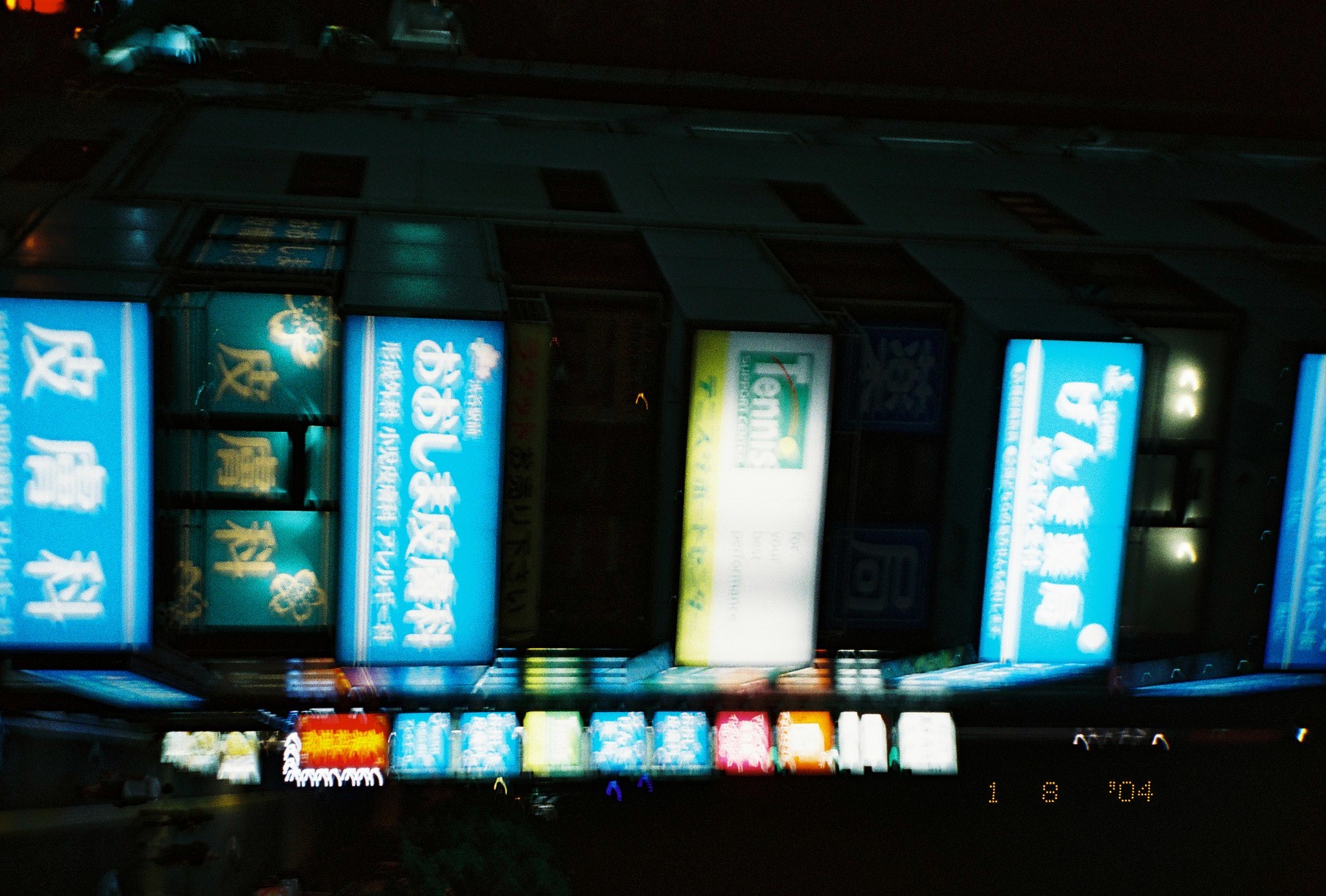A slightly soft second view of the same signage tower shows most panels, including げんき薬局 and Tennis SUPPORT CENTER, still clearly legible.