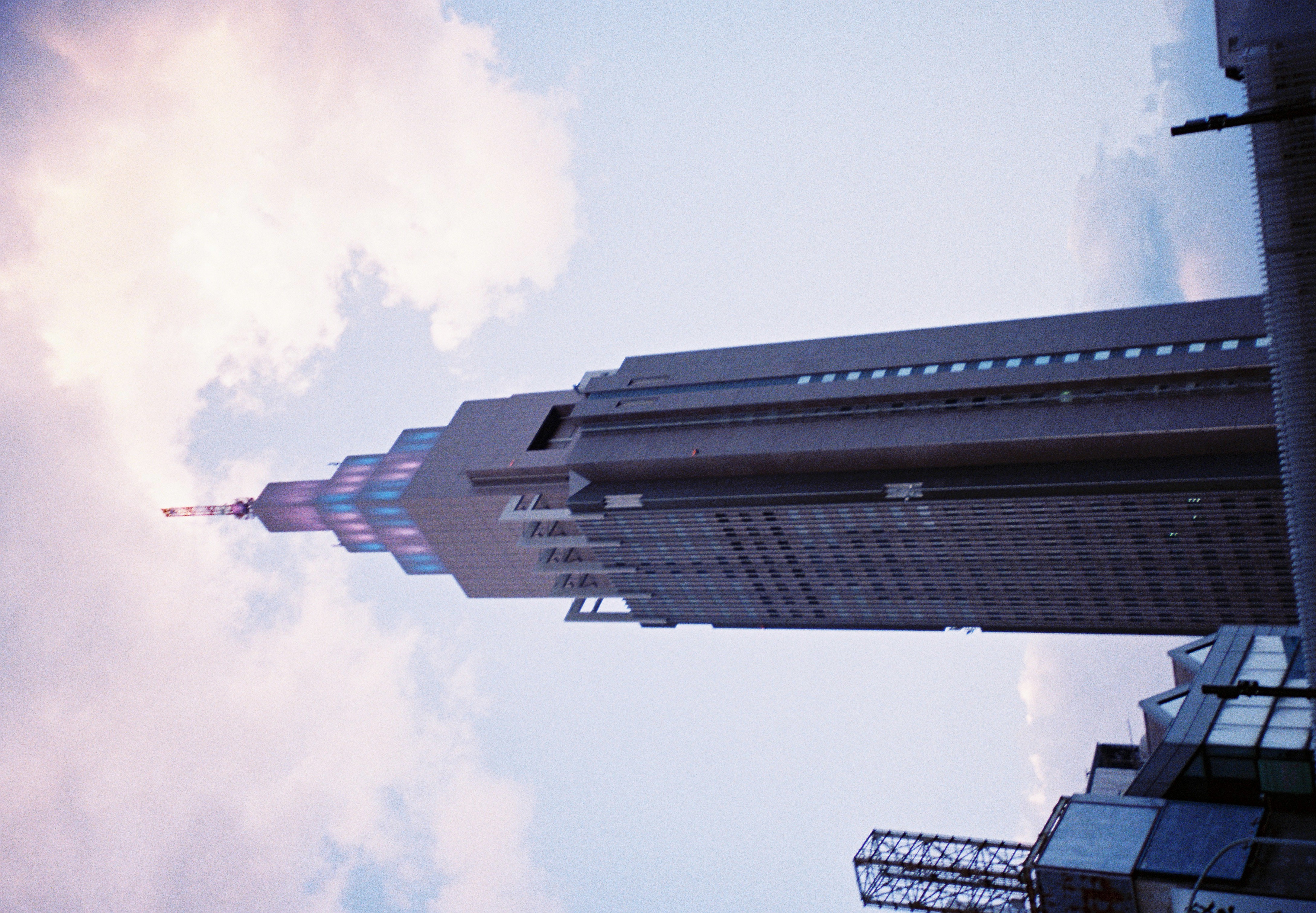 A narrow stepped tower rises above lower rooftops into a pale sky mottled with soft clouds.