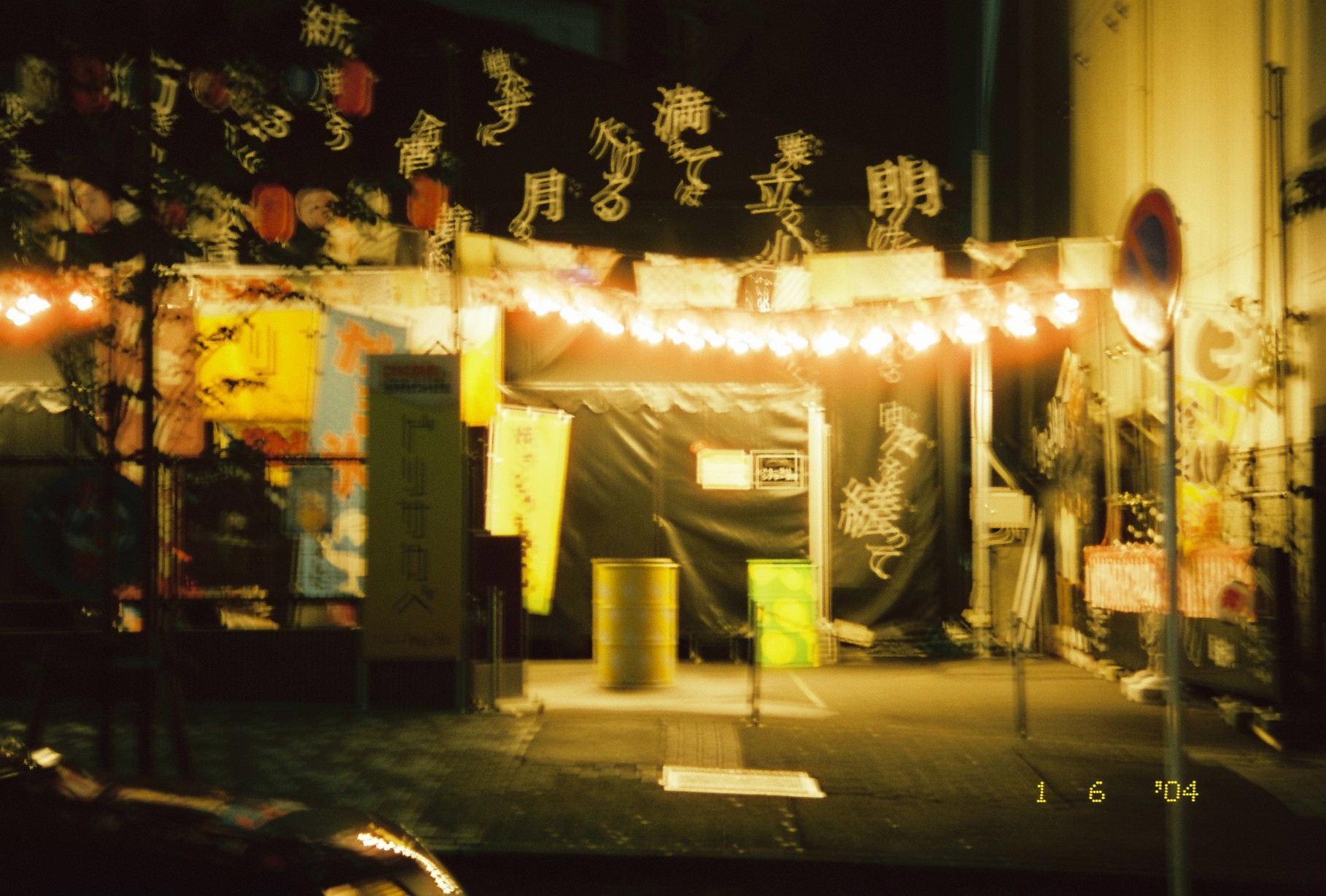 A street stall glows under a string of bare bulbs and round lanterns, with large cursive Japanese calligraphy overlaid across the dark sky above.